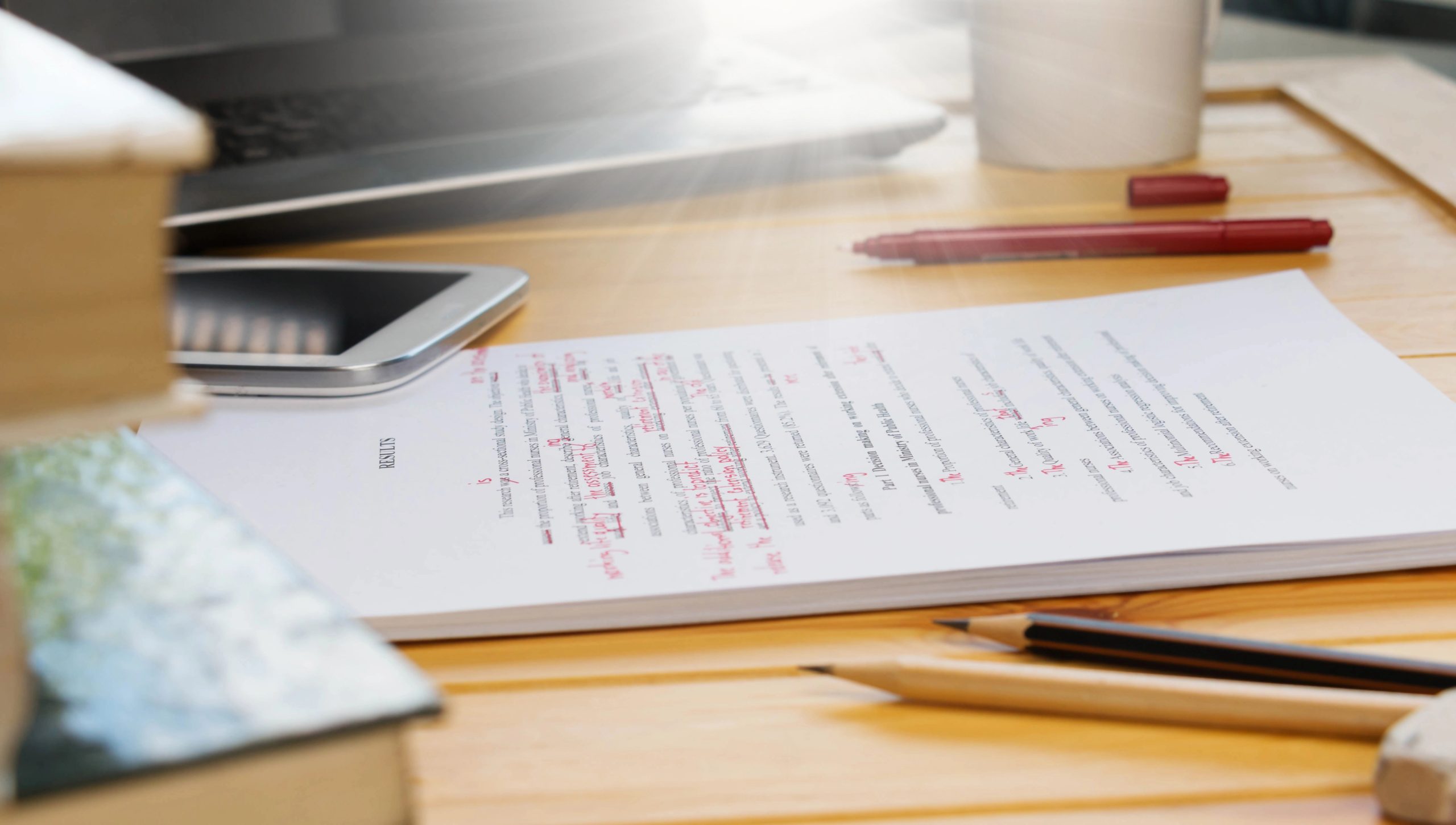 An image of a notepad on a desk with writing on it, including red-line ink to showcase editing skills