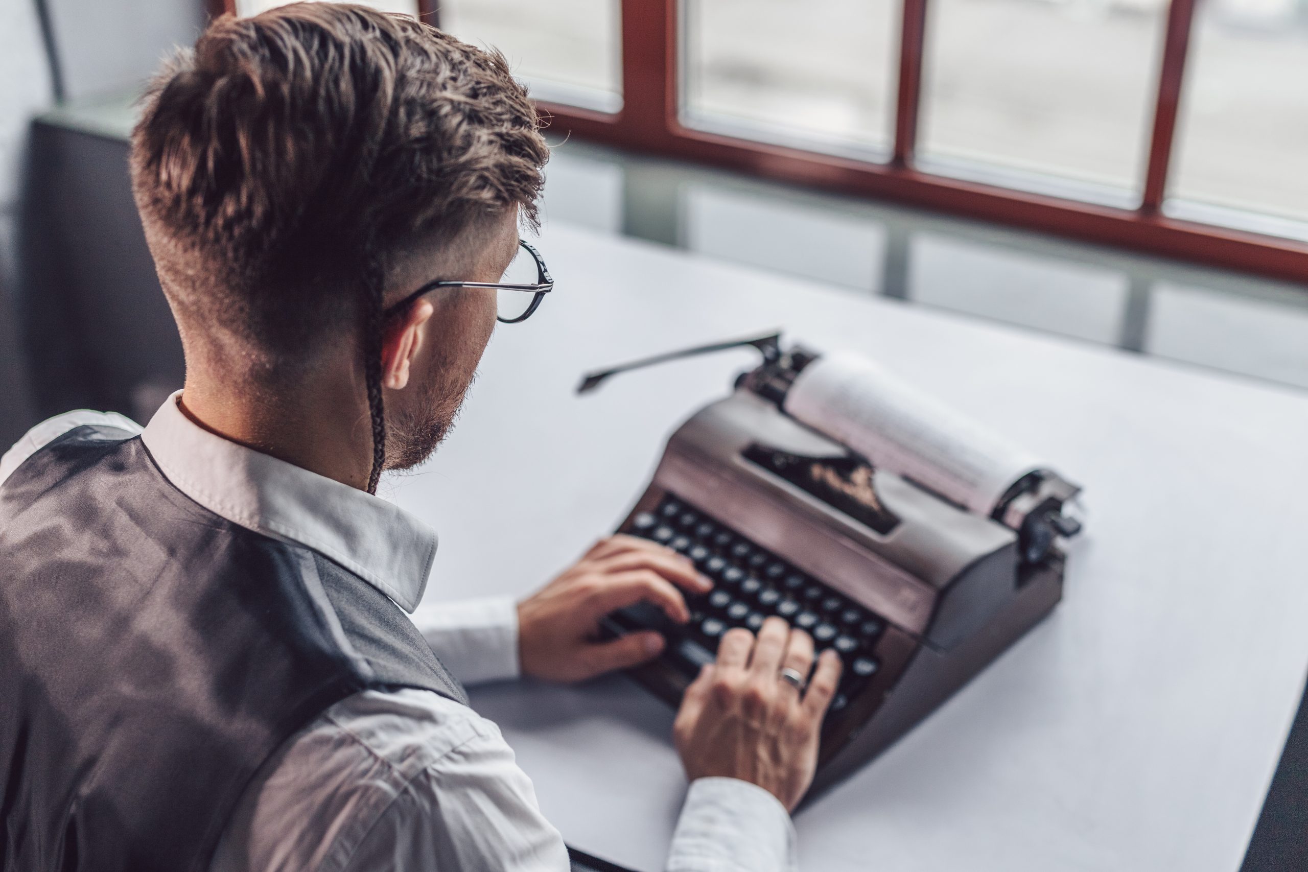 Young man with a retro typewriter at work in the office